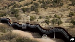 FILE - This March 2, 2019, file photo, shows a Customs and Border Control agent patrolling on the U.S. side of a razor-wire-covered border wall along the Mexico east of Nogales, Ariz.