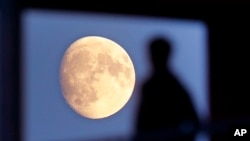 FILE - A student leaves his residence as the moon rises over Frankfurt, Germany, Nov. 1, 2017. 