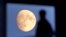 FILE - A student leaves his residence as the moon rises over Frankfurt, Germany, Nov. 1, 2017. 