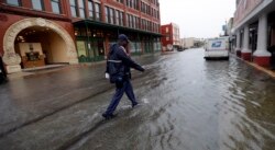 A postman walks through the flooded streets from Tropical Depression Imelda as he deliver mail, Sept. 18, 2019, in Galveston, Texas.