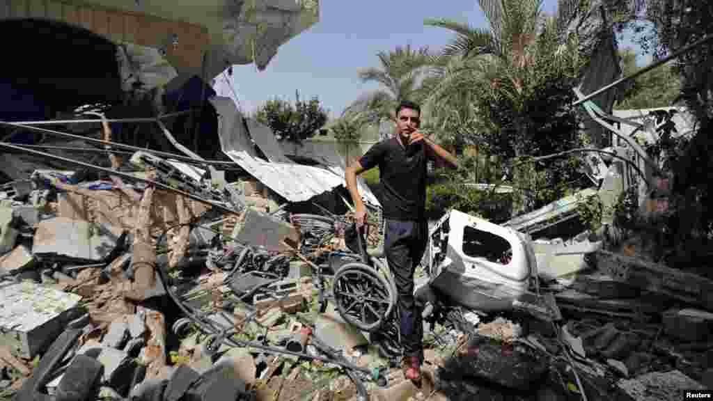 A Palestinian carries a damaged wheelchair as he walks amidst the debris of a rehabilitation center, which police said was struck by a shell from an Israeli tank, in the northern Gaza Strip, July 12, 2014.