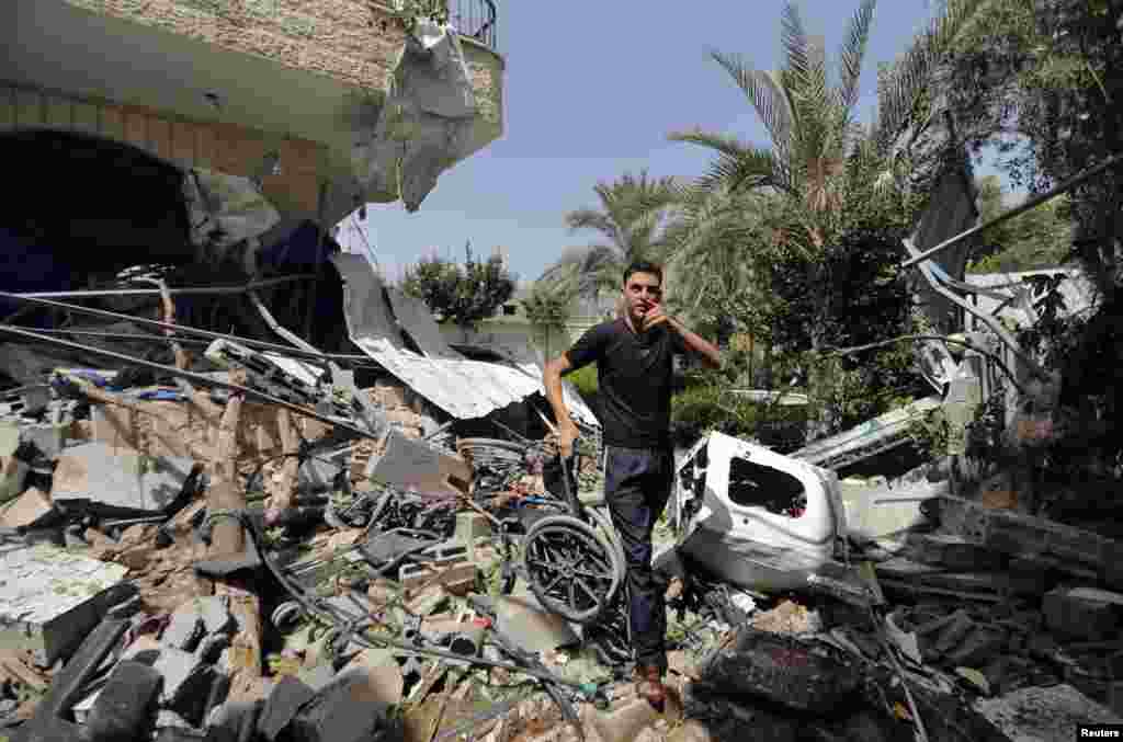 A Palestinian carries a damaged wheelchair as he walks amidst the debris of a rehabilitation center, which police said was struck by a shell from an Israeli tank, in the northern Gaza Strip, July 12, 2014.