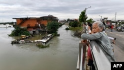 極端氣候下，這個夏季中國多個地方遭受暴雨襲擊釀洪災。圖為2024年7月2日，江西省九江市洪峰過後，當地居民看著街上被淹沒的建築物。