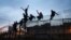 FILE - Sub-Saharan migrants climb over a metallic fence that divides Morocco and the Spanish enclave of Melilla, March 28, 2014. 