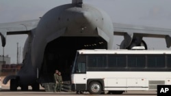 Un avión militar espera a migrantes que suben a un autobús en Fort Bliss en El Paso, Texas, el 30 de enero de 2025, antes de deportarlos a Guatemala.