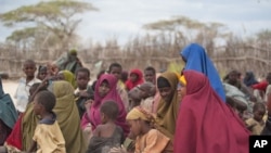 Mothers sit with their children in a compound for internally displaced persons (IDPs) in the Somali border town of Dhobley on August 11, 2011