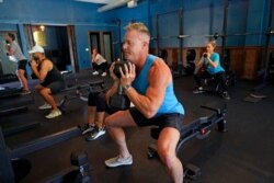 FILE - Scott Johnson, foreground, participates in a fitness class at Lift Society May 21, 2021, in Studio City, Calif. California will no longer require social distancing and will allow full capacity for businesses when the state reopens on June 15.