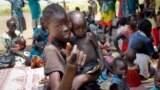 In this photo taken Sept. 16, 2016, a young girl holds a child at a UNICEF clinic for severely malnourished children in Aweil, South Sudan.