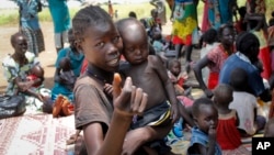 In this photo taken Sept. 16, 2016, a young girl holds a child at a UNICEF clinic for severely malnourished children in Aweil, South Sudan.