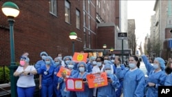 Nurses and medical workers react as police officers and pedestrians cheer them outside Lenox Hill Hospital, April 15, 2020, in New York.