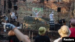 Artist performs while volunteers remove debris from the House of a Culture in the village of Yahidne