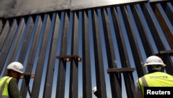 FILE - Construction workers check a new section of bollard wall in Santa Teresa, N.M., as seen from the Mexican side of the border, April 23, 2018, on the outskirts of Ciudad Juarez, Mexico.