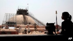 FILE - A Nepalese woman looks at the reconstruction work at the Boudhanath Stupa which was damaged in last year's earthquake in Kathmandu, Nepal, Monday, April 25, 2016.