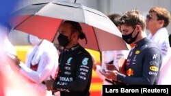 Lewis Hamilton, pembalap Mercedes dan Max Verstappen, pembalap Red Bull, sebelum memulai balapan F1 di Silverstone Circuit, di Silverston, Inggris, Minggu, 18 Juli 2021. (Foto: Lars Baron/Reuters) 