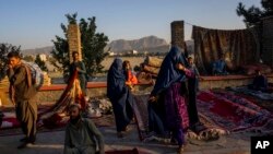 FILE - Women walk through a secondhand market where many families sold belongings before leaving the country or because of financial struggle, in Kabul, Afghanistan, Sept. 15, 2021. The question of how the world can aid Afghans without assisting the Taliban remains troubling.