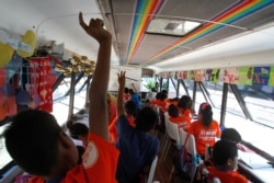 Migrant children take English lessons at a bus converted in a classroom as part of Schools On Wheels program by California's 'Yes We Can' organization, in Tijuana, Mexico, Aug. 2, 2019.