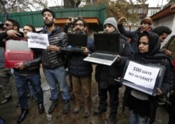 FILE - Kashmiri journalists display laptops and placards during a protest demanding restoration of internet service, in Srinagar, Nov. 12, 2019.