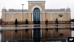 FILE - Rain drops fall on a puddle in an empty parking lot outside a Lord & Taylor store, closed due to the coronavirus outbreak, in Salem, New Hampshire, April 3, 2020. 