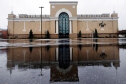 FILE - Rain drops fall on a puddle in an empty parking lot outside a Lord & Taylor store, closed due to the coronavirus outbreak, in Salem, New Hampshire, April 3, 2020.