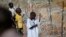 Internally displaced boys stand next to barbed wire inside a United Nations Missions in Sudan (UNMIS) compound in Juba, South Sudan, Dec. 19, 2013. 