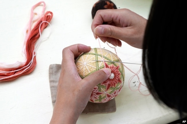 FILE - A staff member works on the temari at Sanuki Kagari Temari in Kawaramachi, Kagawa prefecture, Japan, on Sept. 5, 2024. (AP Photo/Ayaka McGill)