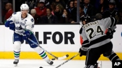 FILE - Vancouver Canucks center Henrik Sedin, left, of Sweden, passes the puck against Los Angeles Kings defenseman Derek Forbort during the first period of an NHL hockey game in Los Angeles, March 4, 2017. The NHL will play its first games in China this fall when the Kings and Canucks meet in Beijing and Shanghai.