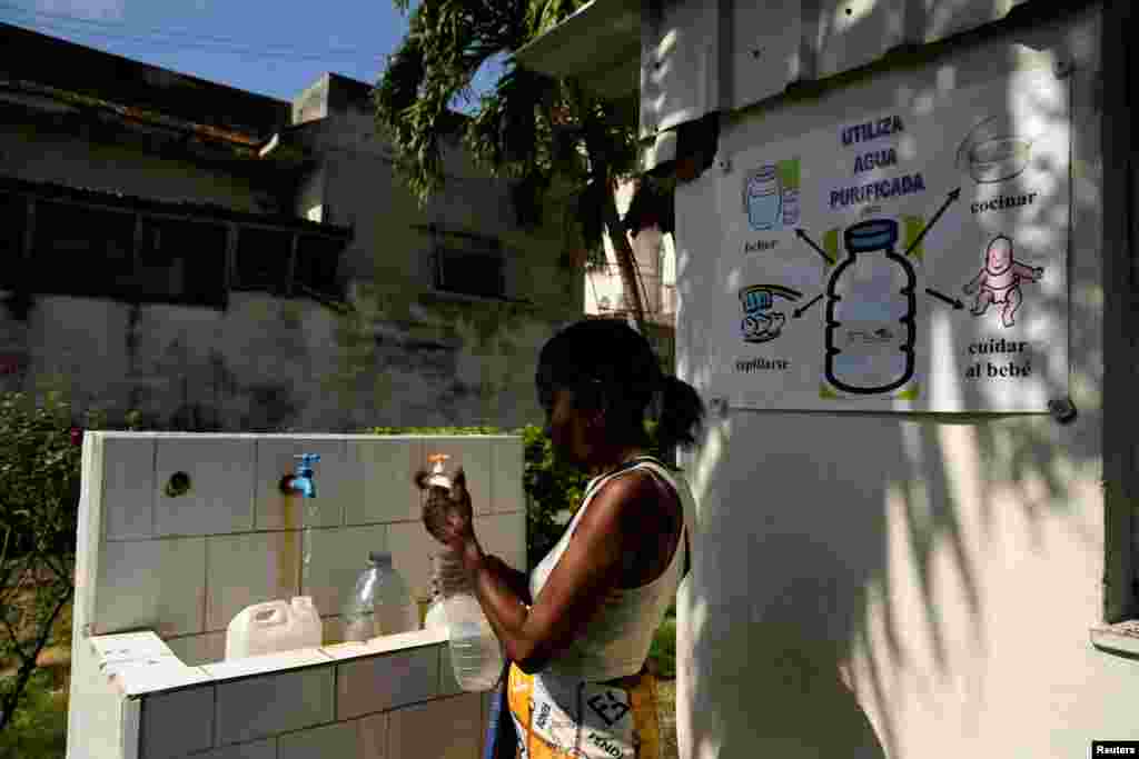 Una mujer llena botellas con agua de un grupo de la iglesia que ofrece a los residentes pequeñas cantidades del líquido para frenar la escasez, en La Habana, Cuba, el 12 de septiembre.