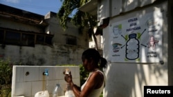 Seorang perempuan tampak mengisi botol yang ia bawa dengan air dari sebuah kelompok gereja yang menawarkan bantuan air kepada warga di Havana, Kuba, pada 12 September 2024. (Foto: Reuters/Norlys Perez)