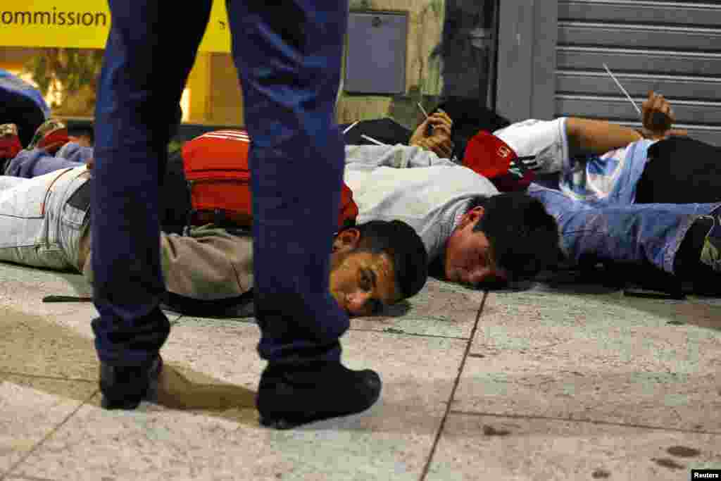 A police officer stands guard next to people detained during riots after Argentina lost to Germany in their 2014 World Cup final soccer match in Brazil, in downtown Buenos Aires, July 13, 2014.