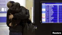 A couple embraces next to a flight information board at Pulkovo airport in St. Petersburg, Oct. 31, 2015. 