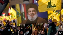 Pendukung Hizbullah mengibarkan potret pemimpin Hizbullah Sayyed Hassan Nasrallah dan bendera kelompok mereka, selama kampanye pemilihan, di pinggiran selatan Beirut, Lebanon, Selasa, 10 Mei 2022. (Foto: AP)