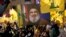 Pendukung Hizbullah mengibarkan potret pemimpin Hizbullah Sayyed Hassan Nasrallah dan bendera kelompok mereka, selama kampanye pemilihan, di pinggiran selatan Beirut, Lebanon, Selasa, 10 Mei 2022. (Foto: AP)