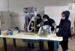 FILE - A group of young girls are developing two types of cheap ventilator devices using Toyota car spare parts to help the fight against the coronavirus pandemic in Herat province west of Kabul, Afghanistan, April 8, 2020.