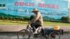 A man cycles past a propaganda board with the words "Organize well G20, be a good host" in Hangzhou in eastern China's Zhejiang province, Sept. 1, 2016.