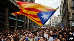 Manifestantes con la bandera independentista catalana protestan frente a una estación de policía en Barcelona, el martes, 3 de octubre, de 2017.
