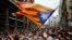 Manifestantes con la bandera independentista catalana protestan frente a una estación de policía en Barcelona, el martes, 3 de octubre, de 2017.
