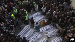 People from the Shiite Hazara community gather around the bodies of coal mine workers who were killed by unknown gunmen near the Machh coal field, in Quetta, Pakistan, Jan. 3, 2021. 