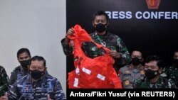 Seorang personel militer memegang baju keselamatan awak yang diyakini berasal dari kapal selam TNI AL KRI Nanggala 402 yang tenggelam saat jumpa pers di Bandara I Gusti Ngurah Rai, Bali, 25 April 2021. (Foto: Antara/Fikri Yusuf via REUTERS)