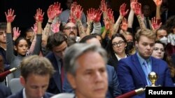 Manifestantes pacíficos levantan manos pintadas de rojo simulando la sangre, durante una audiencia en el el Congreso de EEUU el martes 31 de octubre de 2023.