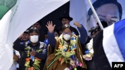 El presidente electo de Bolivia, Luis Arce (C) y el vicepresidente electo, David Choquehuanca, celebran su victoria en las elecciones generales durante un mitin en El Alto, Bolivia, el 24 de octubre de 2020.