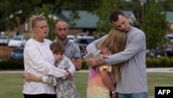 FILE - A family embraces during a vigil for the victims of the Apalachee High School shooting at Jug Tavern Park in Winder, Georgia, on September 4, 2024, after a shooting took place. (Photo by CHRISTIAN MONTERROSA / AFP)