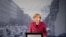 FILE - German Chancellor Angela Merkel speaks near a photograph of the former Berlin Wall, which had separated Germany’s west and Communist east for decades until late 1989. The country’s ruling coalition agreed to increase pensions for former East Germans.
