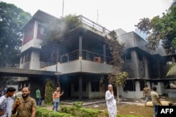 Orang-orang berkumpul di Museum Peringatan Bangabandhu Sheikh Mujibur Rahman, pendiri negara Bangladesh dan orang tua Perdana Menteri terguling Sheikh Hasina, setelah museum tersebut dibakar oleh pengunjuk rasa antipemerintah di Dhaka pada 6 Agustus 2024. (Foto: AFP)