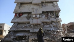 Seorang wanita melihat sebuah bangunan, yang rusak selama operasi keamanan dan bentrokan antara pasukan keamanan Turki dan militan Kurdi, di kota tenggara Cizre di provinsi Sirnak, Turki, 2 Maret 2016. (Foto: Reuters)