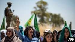 FILE - A Syrian Kurdish woman chants slogans during a rally in the countryside of the Hasakah province, Syria, June 27, 2020, to protest deadly Turkish offensives in northeastern areas of the country.