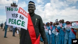 Des Sud-Soudanais portent des pancartes en attendant l'arrivée du président du Soudan du Sud, Salva Kiir, à l'aéroport de Juba, au Soudan du Sud, le 22 juin 2018.