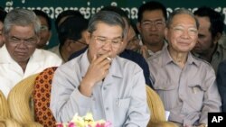 Cambodia's Prime Minister Hun Sen, center, smokes as he sits with Interior Minister Sar Kheng, left, and Finance Minister Keat Chhun, right, during the inauguration of the China-funded construction of a bridge in Mouk Kampoul district, Kandal province, some 20 kilometers (12 miles) north of Phnom Pen, Cambodia, file photo. 