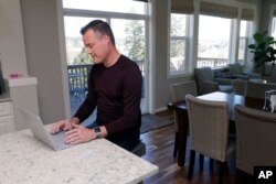 Neal Browning, works on his laptop in the kitchen of his home, March 16, 2020, in Bothell, Washington.