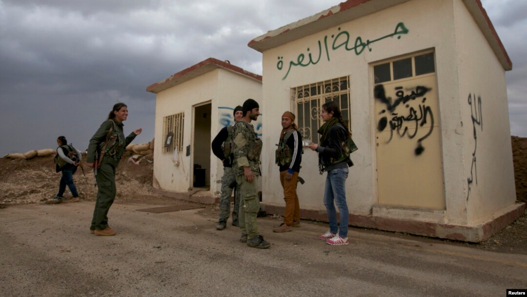 Members of the Kurdish People's Protection Units chat in front of a base captured from an Islamist Syrian rebel group in Al-Rmelan, Qamshli province. Kurdish militias are solidifying a geographic and political presence in the war-torn country.