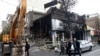 People walk near a burned bank after protests against increased fuel prices in Tehran, Iran, Nov. 20, 2019.